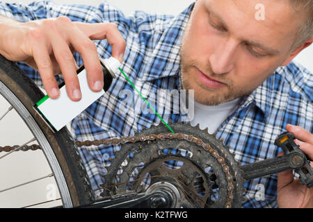 Close-up of Young Man huilage chaîne de bicyclette Banque D'Images