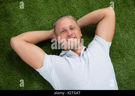 Young Happy Man Lying On Green Grass Banque D'Images