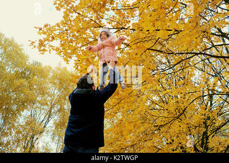 Le père jette l'enfant dans le parc à l'automne. Banque D'Images