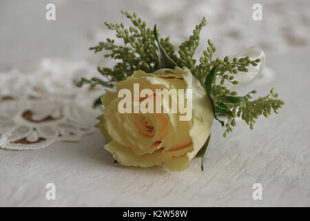 Accessoires de mariage : fresh rose jaune petit bouquet pour boutonnière utilisé pour le marié et les invités du mariage placé sur un linge blanc, de lumière naturelle Banque D'Images