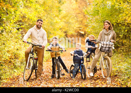 Jeune famille de vêtements chauds à vélo dans le parc en automne Banque D'Images