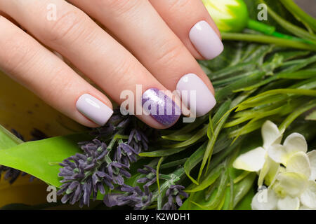 Manucure soignée pourpre sur les mains sur fond de fleurs. Nail design Banque D'Images
