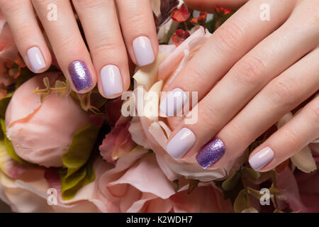 Manucure soignée pourpre sur les mains sur fond de fleurs. Nail design Banque D'Images