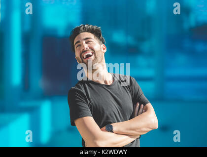 Portrait de jeune homme avec les bras pliés de rire à la suite Banque D'Images