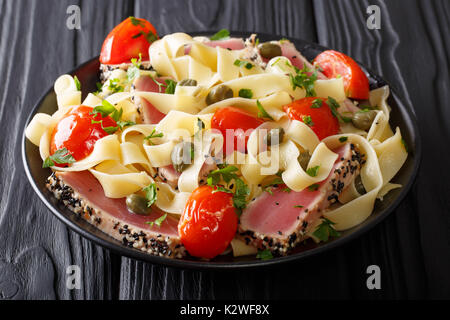 Repas gastronomique : pâtes Fettuccine avec steak de thon et légumes frits libre sur une plaque sur la table horizontale. Banque D'Images