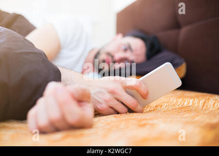 Man reading text message sur son smart phone in bed Banque D'Images