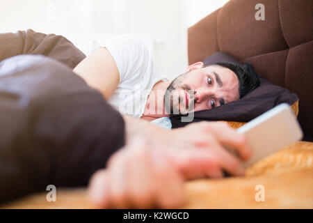 Man reading text message sur son smart phone in bed Banque D'Images