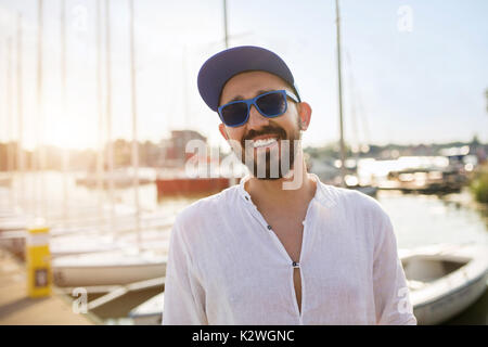Young man standing in location port sur le coucher du soleil et smiling Banque D'Images