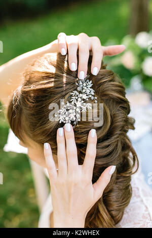 Style, féminité, décoration concepr. dans les cheveux frisés cheveux brun clair de jeune femme il n'y brille avec barrette de diamants en forme de feuilles et fleurs Banque D'Images