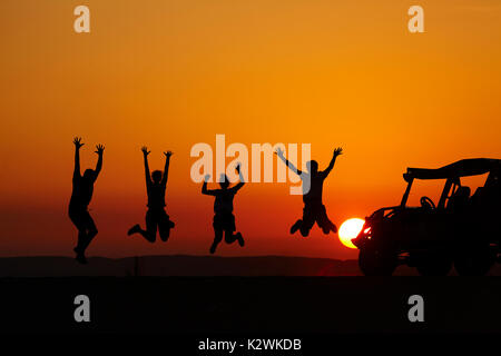 Les touristes sautant au coucher du soleil sur les dunes de sable dans le désert près de l'Oasis de Huacachina, Ica, Pérou, Amérique du Sud (M.) Banque D'Images