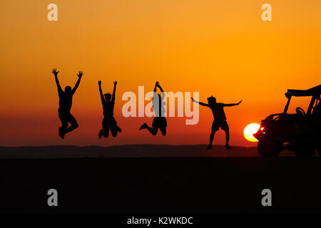 Les touristes sautant au coucher du soleil sur les dunes de sable dans le désert près de l'Oasis de Huacachina, Ica, Pérou, Amérique du Sud (M.) Banque D'Images