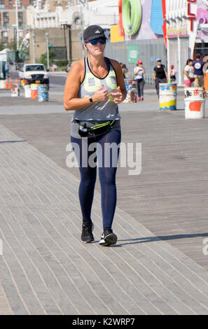 Une femme le jogging sur la promenade sur un matin d'été à Coney Island, Brooklyn, New York Banque D'Images