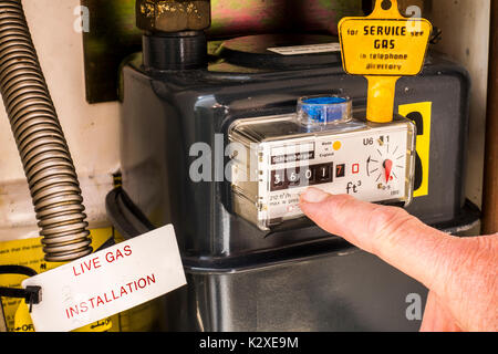 À l'intérieur d'un compteur de gaz armoire avec une touche jaune sur le dessus de l'appareil étanche et un doigt pointé à la lecture de la consommation. East Midlands, Angleterre, Royaume-Uni. Banque D'Images