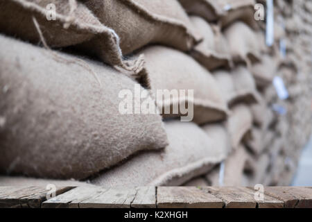 Vieux chanvre sacs contenant coffee bean en entrepôt. sacs empilés en entrepôt avec table en bois pour afficher votre produit. Banque D'Images