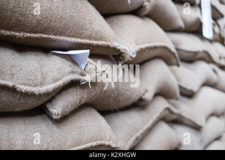 Vieux chanvre sacs contenant coffee bean en entrepôt. sacs empilés en entrepôt. Banque D'Images