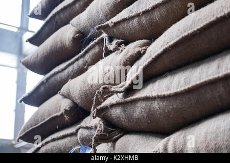 Vieux chanvre sacs contenant coffee bean en entrepôt. sacs empilés en entrepôt. Banque D'Images