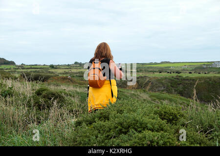 Femme avec sac à dos en tenant l'iphone mobile phone photo le long de la côte entre St Galles's & Porthclais Non en été, Pembrokeshire UK KATHY DEWITT Banque D'Images