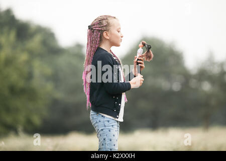 Enfant fille avec des tresses joue avec sa poupée sur marche. Banque D'Images