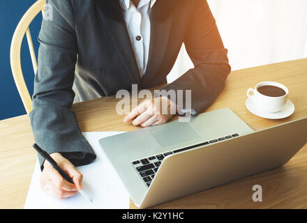 Femme travaille sur table en bois avec coffre et un café chaud Banque D'Images