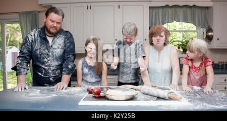 Une famille en colère dans la cuisine après une bataille alimentaire et la cuisson une tarte aux pommes. Banque D'Images