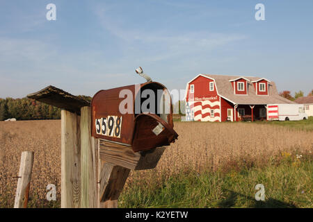 Rusty mail box en premier plan avec ferme et grange rouge en arrière-plan, dans les régions rurales de l'Ohio, États-Unis Banque D'Images