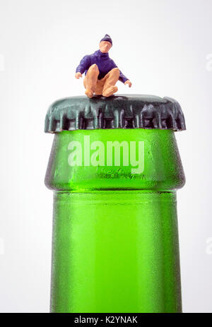 Homme miniature assis sur le dessus d'une bouteille de bière isolé sur fond blanc Banque D'Images