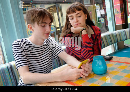 jeune couple adolescent dans un café urbain utilisant un téléphone portable Banque D'Images