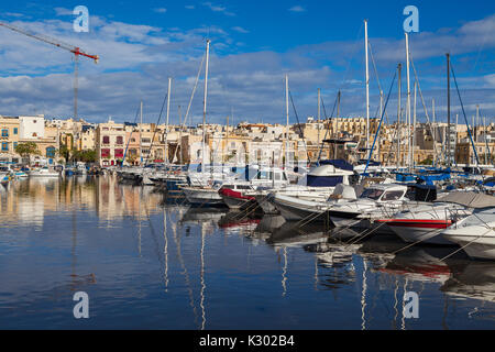 MSIDA, MALTE - 19 octobre 2016 : Beaucoup de beaux bateaux dans un petit port avec cityscape sur l'arrière-plan Banque D'Images