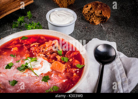 Russe traditionnelle ukrainienne bortsch soupe aux légumes, avec du pain de seigle persil. crème rouleaux, sur table en pierre noire, copy space Banque D'Images