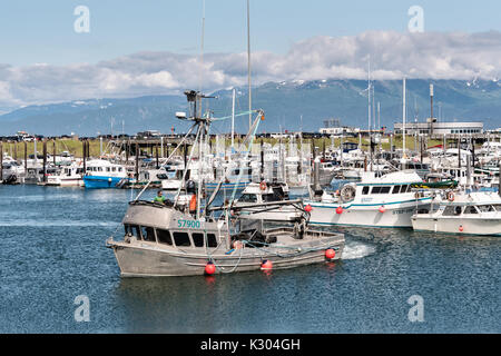 Un petit bateau de pêche revient de l'Kamishak Bay à la ville d'Homer et Port Harbour Marina surplombant les montagnes Kenai dans Homer, Alaska. Banque D'Images