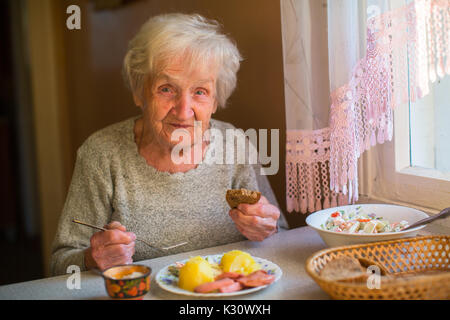 Une femme âgée manger assis à table à dîner à la maison. Banque D'Images