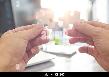 Jeune homme d'essayer de connecter deux morceau de puzzle avec sun flare et fond flou,symbole de l'association et connexion. stratégie d'entreprise. Banque D'Images