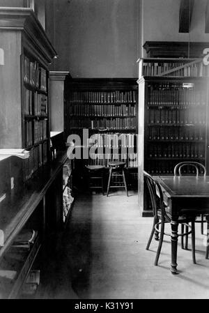 Photographie sépia de la bibliothèque à l'intérieur du bâtiment de chimie au vieux campus de l'Université Johns Hopkins, montrant de rechercher des tables avec des chaises dans entre les piles de livres et registres séparés par des fenêtres lumineuses, Baltimore, Maryland, 1918. Banque D'Images