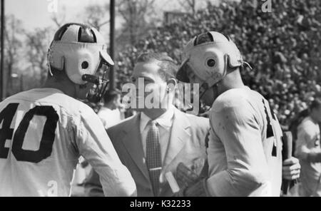 Sépia photographie candide de deux co-capitaines de l'équipe de crosse à l'Université Johns Hopkins, Joe Sollers et Byron Forbush, en uniforme et coiffures, serrant la main de l'entraîneur Smith à la fin du match, Baltimore, Maryland, juin, 1951. Banque D'Images