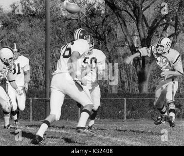 L'Université Johns Hopkins quarterback lance le football en tant que deux joueurs de l'équipe adverse s'approcher de lui pour un s'attaquer à la Johns Hopkins University, Baltimore, Maryland, 1980. Banque D'Images