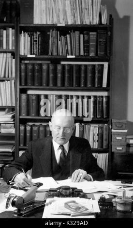 Portrait de Candide Manager de la Johns Hopkins Press Christian William Dittus écrit à son bureau entouré par des journaux et des livres, 1940. Banque D'Images