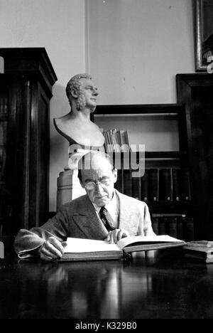 Portrait de Candide Paul Emile Dumont, Professeur de sanskrit et d'Indologie à l'Université Johns Hopkins, assis à un bureau de la lecture, 1951. Banque D'Images