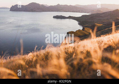 Coucher du soleil avec vue sur le paysage vallonné de la ligne côtière en Crimée, Koktebel. Printemps incroyable avec champ herbe plumes Banque D'Images