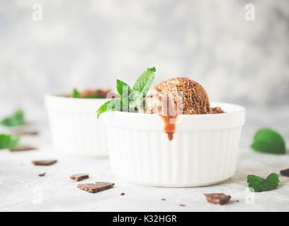 Glace à la menthe chocolat dans des bols blancs avec des morceaux de chocolat et de feuilles de menthe sur une table en marbre, selective focus, haute résolution Banque D'Images