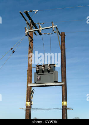 Transformateur haute tension de distribution d'électricité monté sur poteau Schneider Electric sur UK National Grid monté entre deux poteaux en bois Banque D'Images