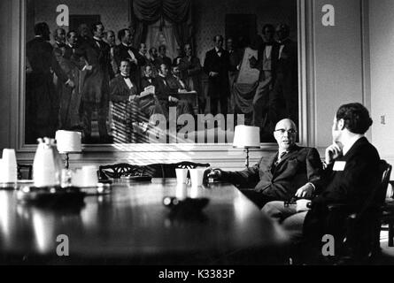 Portrait candide de l'Université Johns Hopkins, président Milton S. Eisenhower (à gauche) assis à une grande table et de parler à un chiffre non identifié au cours de la Milton S. Eisenhower 1971 Symposium, une série de conférences de l'Université John Hopkins, à Baltimore, Maryland, 1971. Banque D'Images