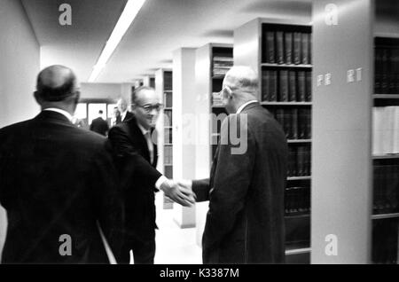 Portrait de Candide 34e président des États-Unis Dwight D. Eisenhower (à droite) serre la main de fonctionnaire du Département d'État Francis Orlando Wilcox (centre) dans la bibliothèque de Milton S. Eisenhower sur l'Homewood campus de l'Université Johns Hopkins à Baltimore, Maryland, 1965. Banque D'Images