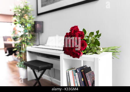 Bouquet de roses rouges sur le tableau blanc avec piano blanc en arrière-plan Banque D'Images