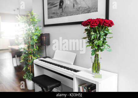 Bouquet de roses rouges sur le tableau blanc avec piano blanc en arrière-plan Banque D'Images
