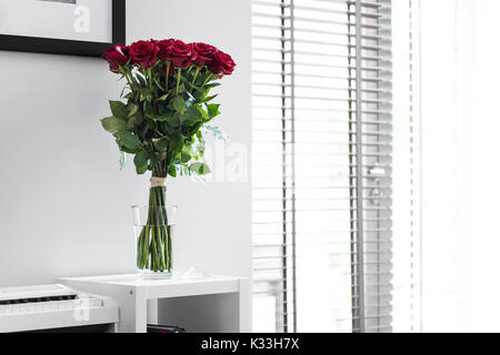 Bouquet de roses rouges sur le tableau blanc avec piano blanc en arrière-plan Banque D'Images
