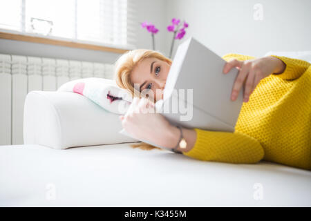 Une photo de jeune femme couché sur la table et la lecture de livre. Banque D'Images