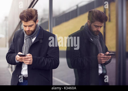 Une photo de jeunes, la mode des buinessman en utilisant le téléphone mobile. Il se tient à l'extérieur. Banque D'Images