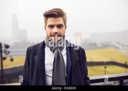 Une photo de jeune, beau homme portant un manteau et d'un châle. C'est regardant droit dans la caméra. Banque D'Images