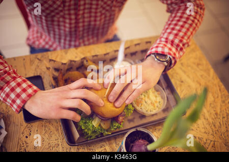 Une photo de man eating hamburger et salade au bar. Banque D'Images