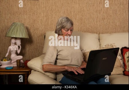 Femme âgée à l'aide d'un ordinateur portable pour faire des achats en ligne Banque D'Images